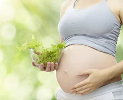 mujer embarazada comiendo vitamina acido folico