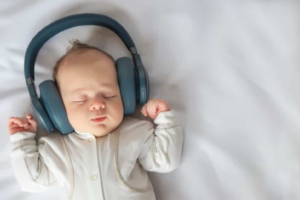 bebe recien nacido sonriendo escuchando musica auriculares acostado sabana blanca cuna infancia feliz despreocupada bebe imagen tonificada vista superior primer plano 262398 206